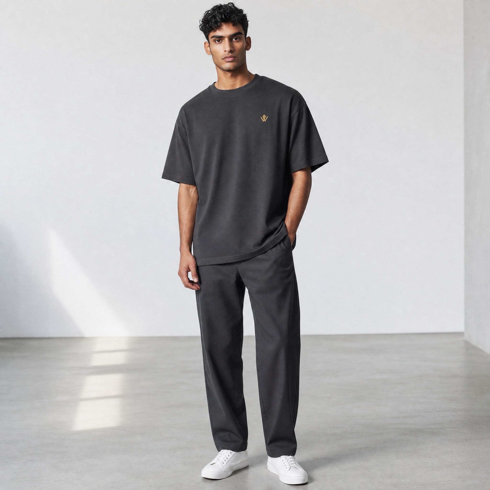 VVID Essential Oversized Tee in charcoal grey with a small gold embroidered logo on the chest. Short sleeves and crew neck.