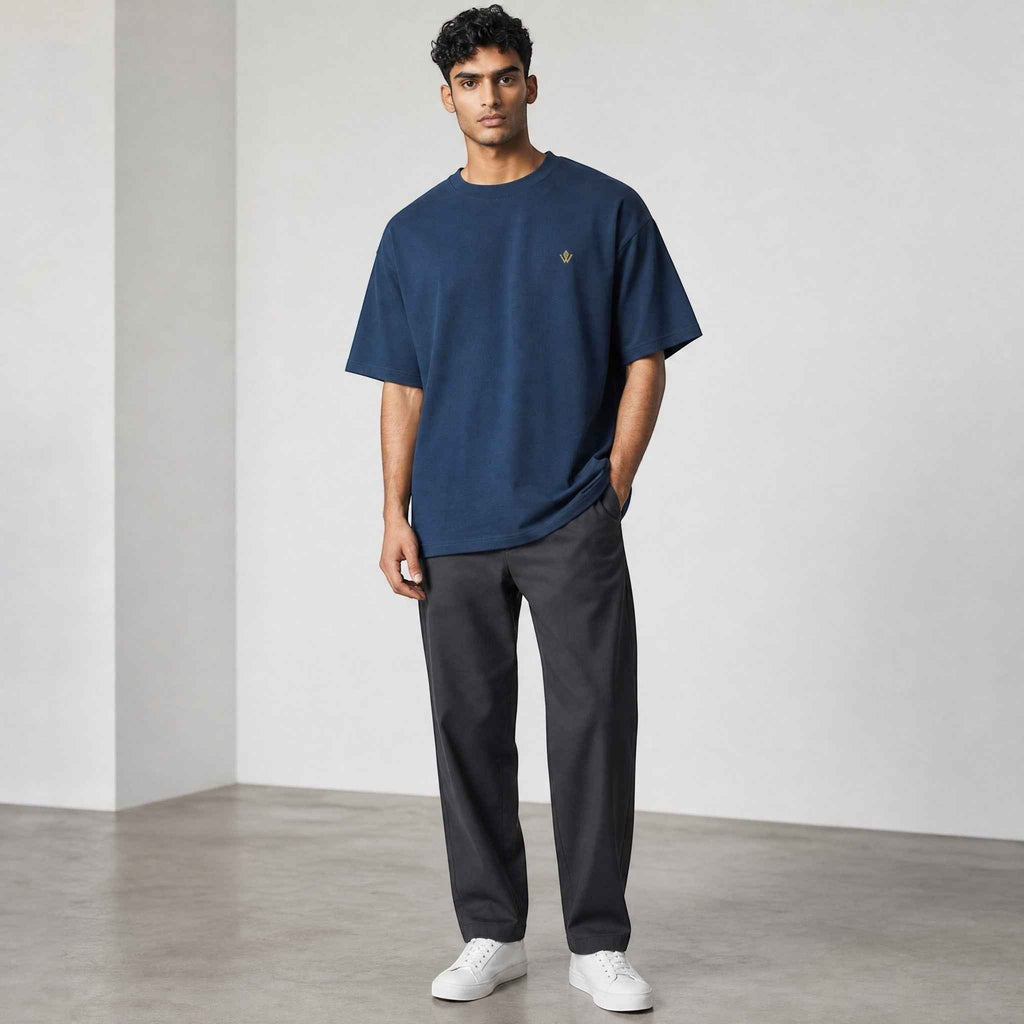 VVID Essential Oversized Tee in navy blue cotton with a small gold embroidered logo on the chest. Model is wearing size M.